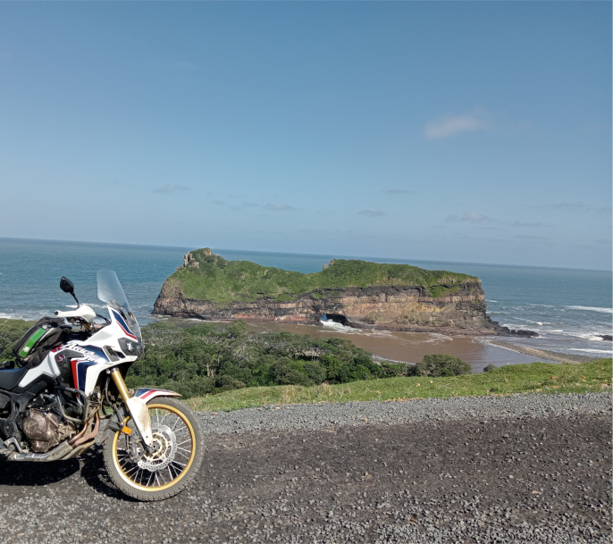 a bike on a road with two hills and the sea in the background