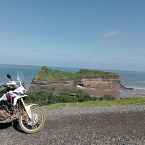 a bike on a road with two hills and the sea in the background